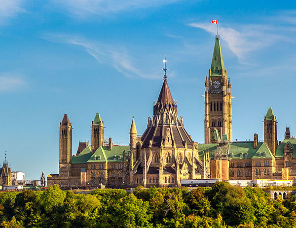 Canadian Parliament Buildings in Ottawa, Ontario. The prominent features include the Peace Tower with a clock and the Canadian flag at the top.