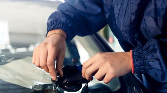A professional auto repairman fixing a crack in a car windshield