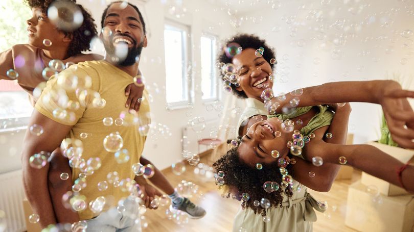 Cheerful family dancing with bubbles in the living room after moving into a new home.