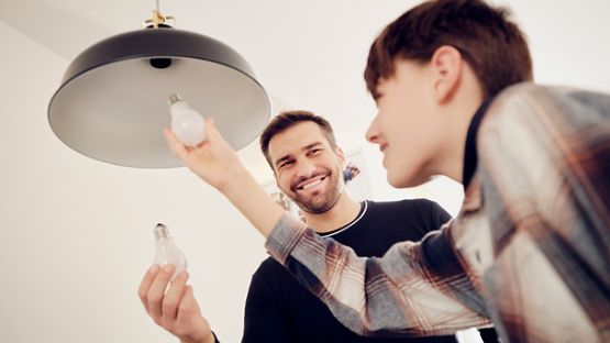 Un père et son fils remplacent une ampoule traditionnelle par une ampoule à DEL à faible consommation énergétique.
