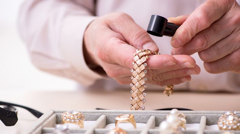 A Jeweler inspecting a  gold and diamond necklace