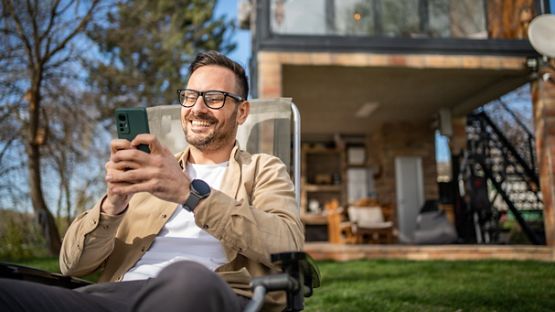A cottager sitting on a chair using a smart electronic device