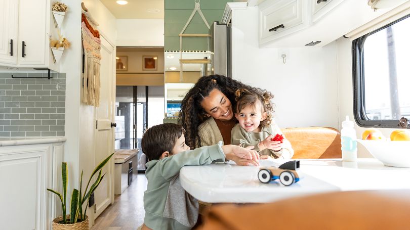 A mother playing with her children inside a luxury RV.  