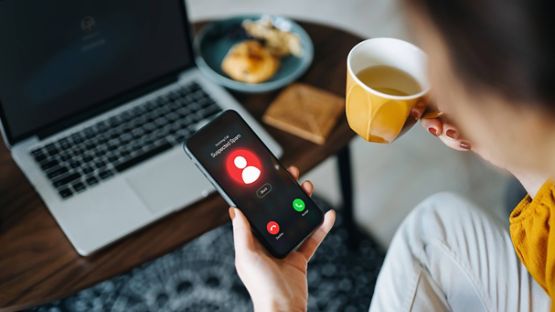 Person looking at cellphone while receiving an incoming scam call