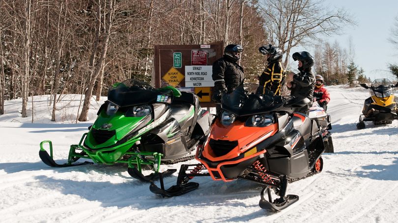 A group of snowmobilers stopping for a break from the trails and checking their planned route.