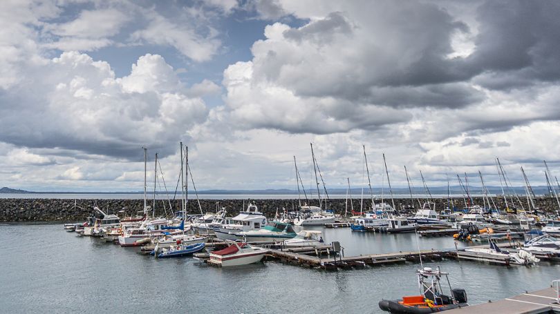 Nuages au-dessus de l’océan annonçant une tempête et bateaux amarrés dans un port de plaisance.