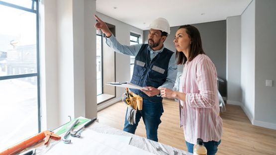 Une femme discute avec son entrepreneur dans une pièce de sa maison en construction. 