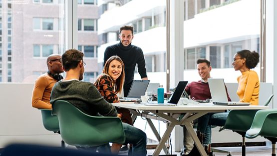 Employees gathered around a large table in a conference room to discuss ideas during a team meeting