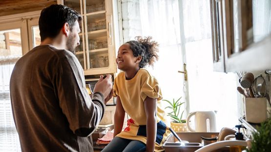 A cheerful father and his daughter having breakfast together in the kitchen