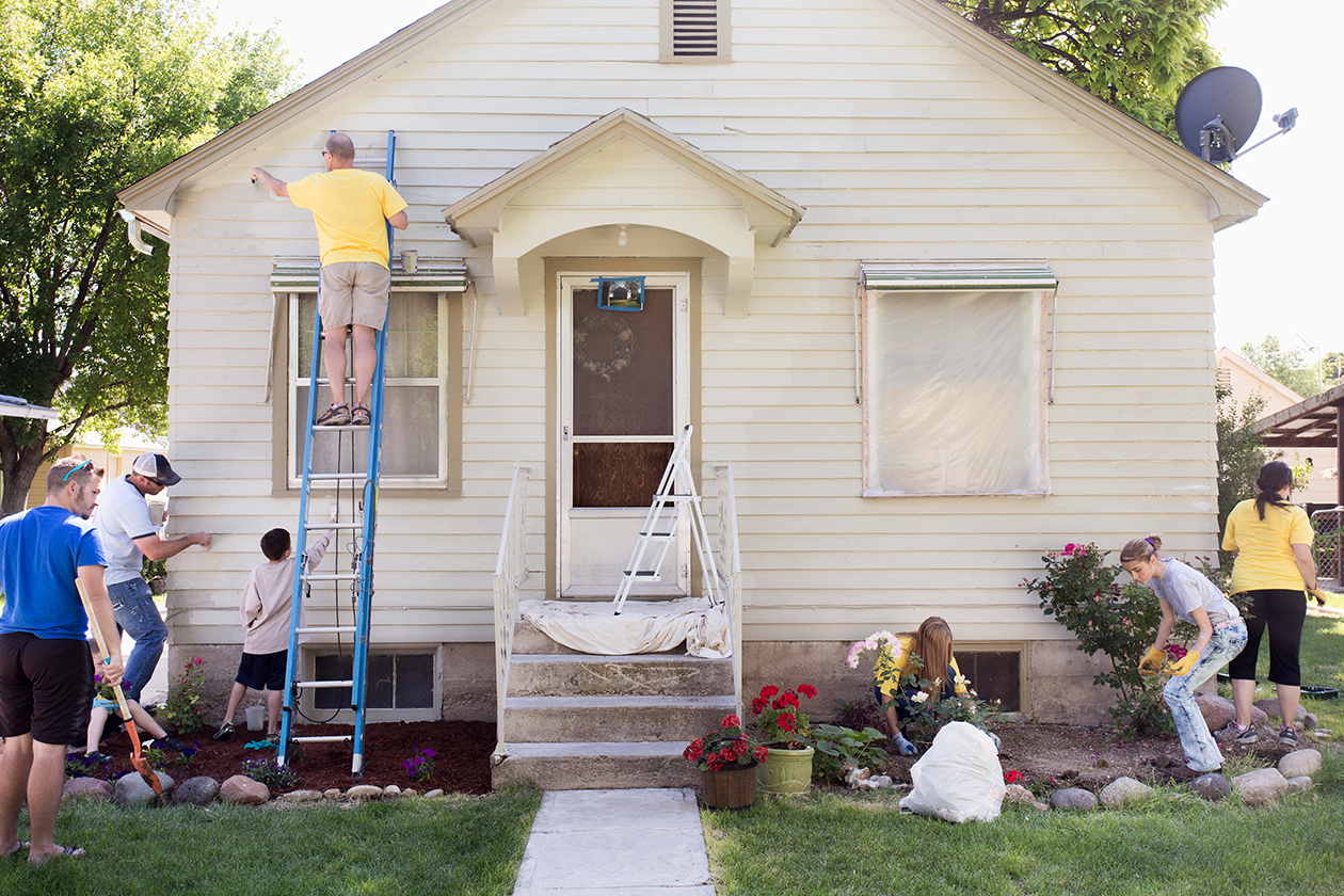 Famille nettoyant le terrain et effectuant des travaux d’entretien devant la maison.