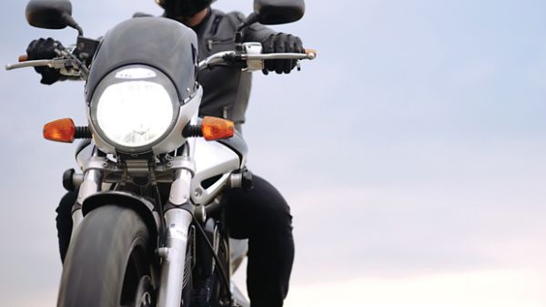 Photo tronquée d’une personne sur sa moto à la tombée du jour