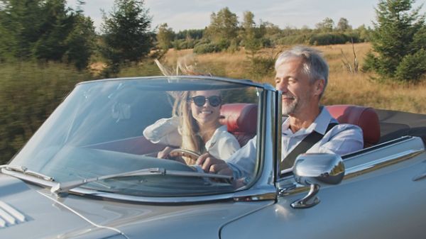 A happy couple enjoying their road trip in a classic car